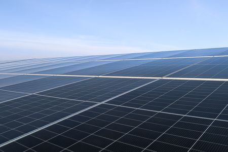 Eine Reihe von Solarpanels, dahinter blauer Himmel.