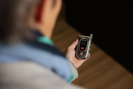 Eine Person hält ein silbernes Klapphandy in der Hand. Das Handy ist geschlossen und einen kleinen Bildschirm auf der Vorderseite.